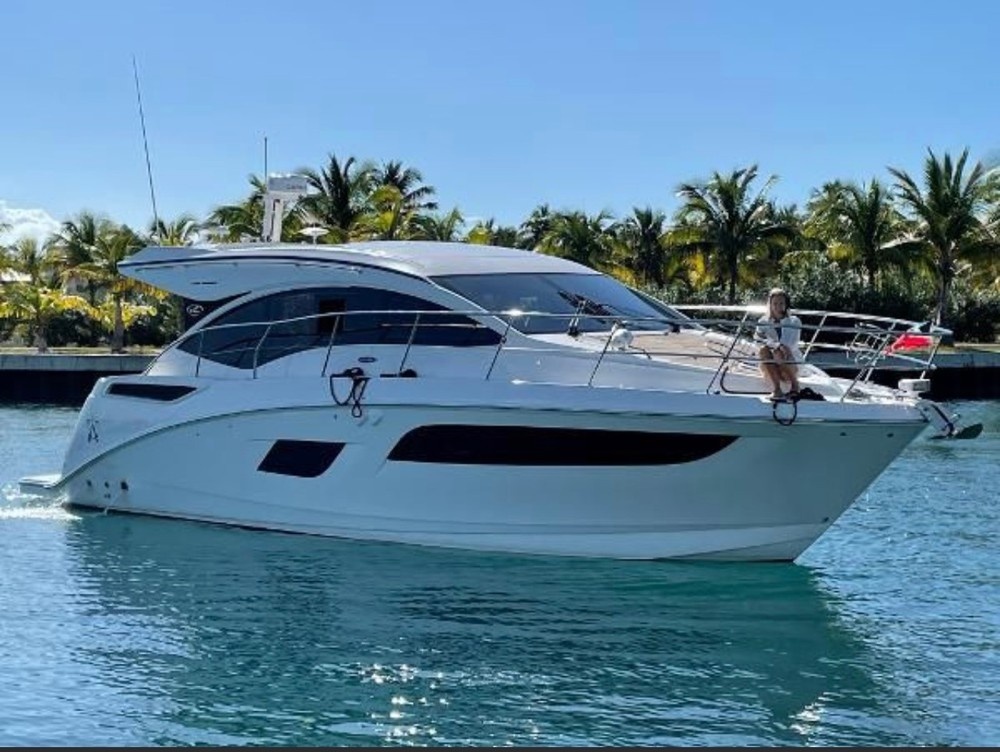 White yacht on water with palm trees in background.