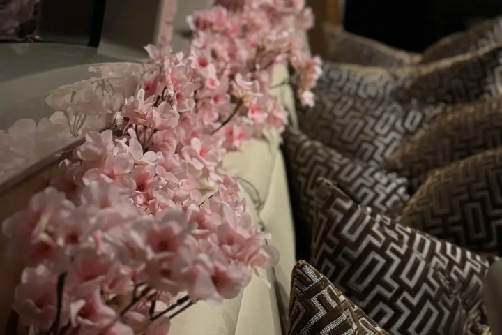 Pink flowers and patterned pillows on a cushioned bench.